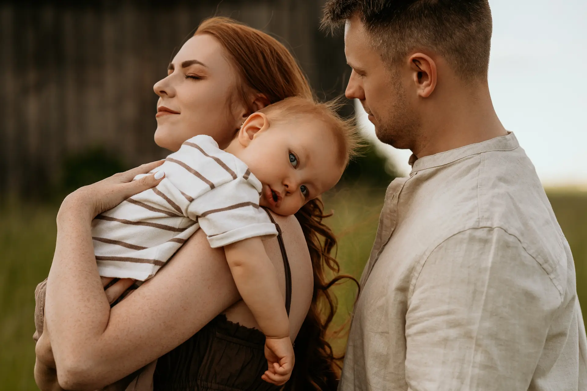 Kobieta trzyma na rękach dziecko, obok stoi mężczyzna