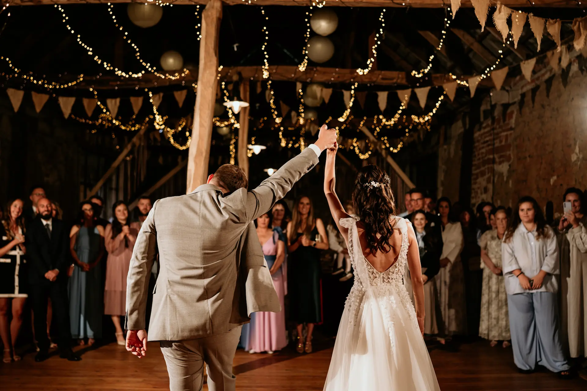 Para młoda tańczy w rustykalnej stodole udekorowanej światłami i girlandami – fotografia ślubna Poznań