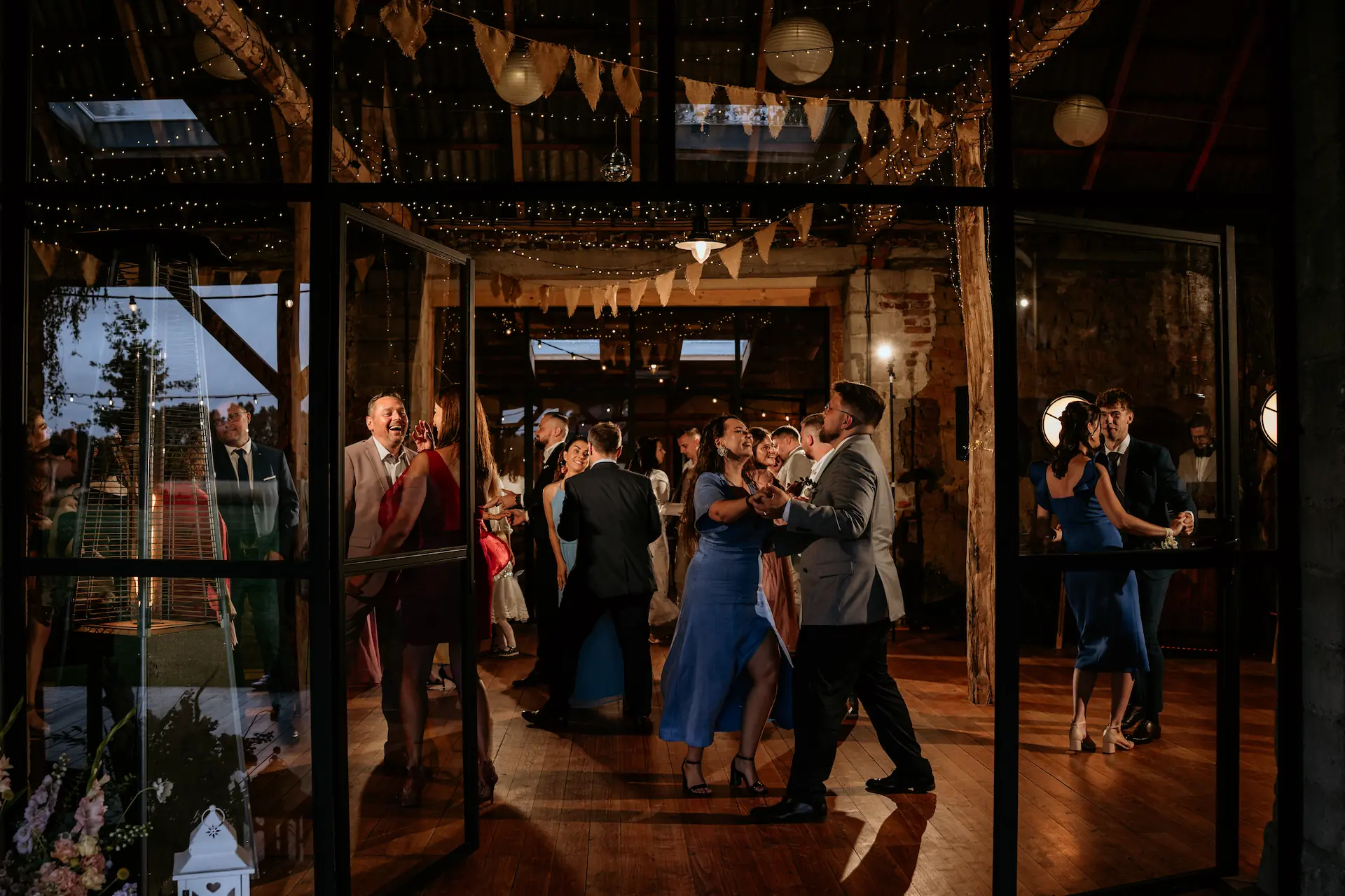 Goście weselni bawią się na parkiecie podczas przyjęcia w stodole – fotografia ślubna Poznań