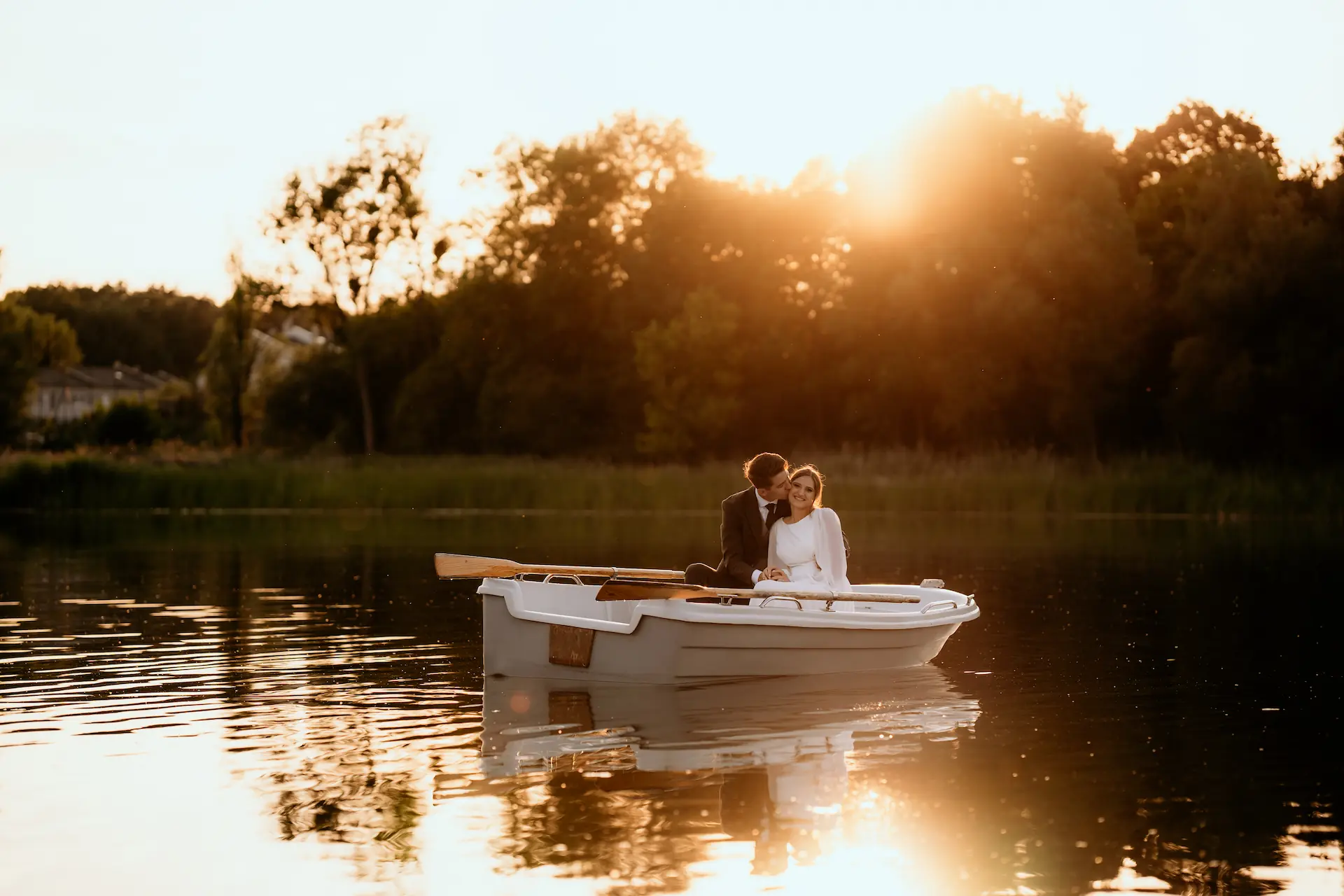 Pan młody obejmuje pannę młodą w łódce podczas zachodu słońca – fotografia ślubna Poznań